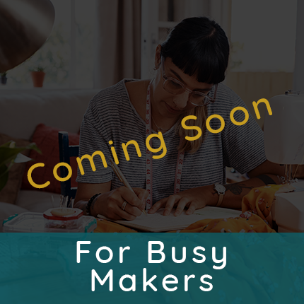 Woman sitting at a sewing table writing in a book representing tutorials for busy makers is coming soon