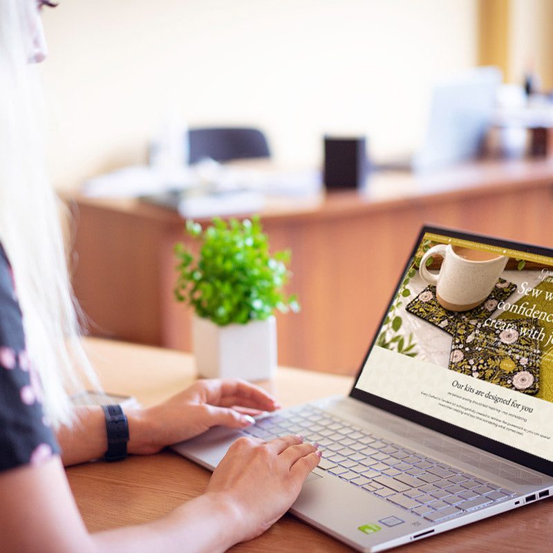 Woman sitting at a computer looking at the Crafted in Tandem Website Homepage.